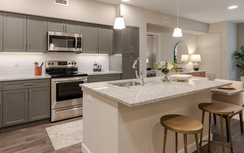Model kitchen at our 55 and over apartments in Loveland, CO, featuring granite countertops and a kitchen island.