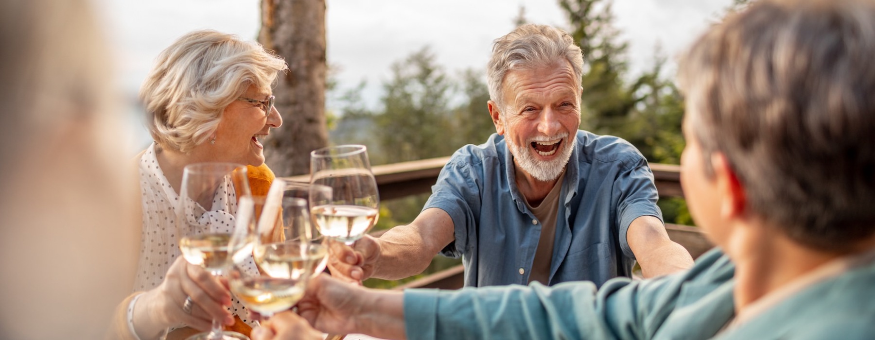 Residents laughing and drinking wine outside at Avenida at Centerra 55+ apartments in Loveland, Colorado.